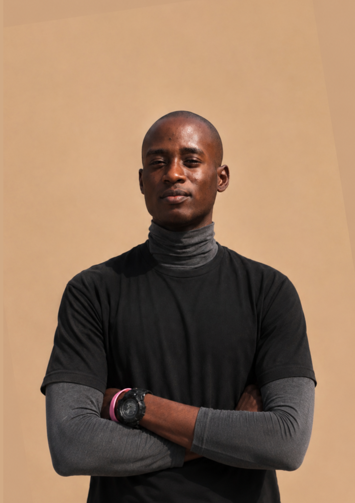 Victor Adetomiwa, arms crossed, photographed against a warm tan background